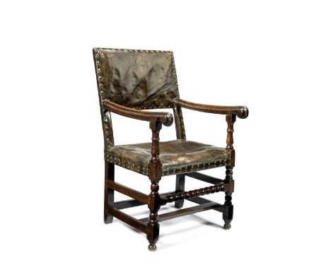 A 17th century oak and leather brass close nailed upholstered armchairWith turned and block carved uprights united by a bobbi