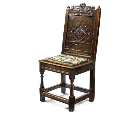 A 17th century carved oak panel back stoolWith a solid seat above turned front legs, with verdure tapestry seat pad, 48cm wid