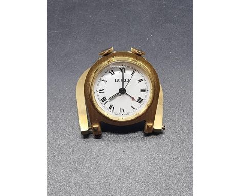 A vintage Gucci gilt metal folding 'horseshoe' manual wind travel alarm clock, 45mm high, in red leather Gucci pouch. 