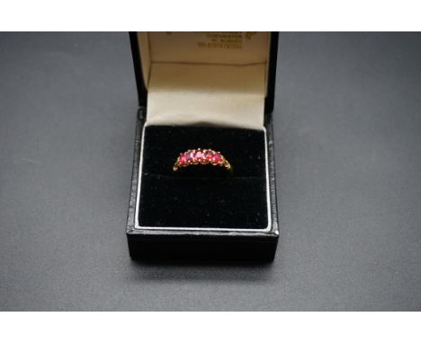 A yellow metal ruby five stone ring, size L1/2. 