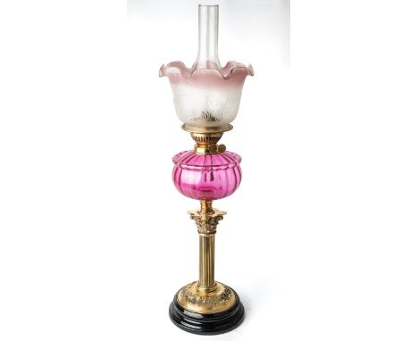 A Victorian oil lamp with a black porcelain base with brass fittings and fluted cranberry  glass body. Approx. height 72cm in