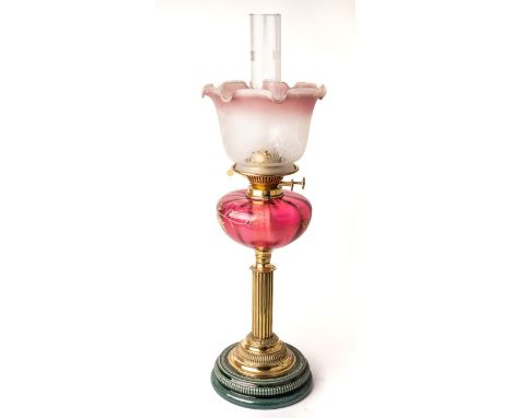 A Victorian oil lamp with majolica base with brass fittings and enamelled cranberry glass body. Approx. height 64cm including