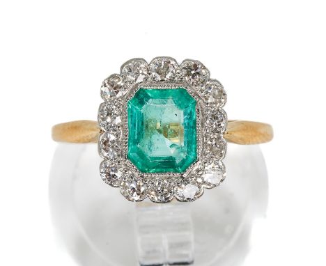 An 18ct yellow gold emerald and diamond ring, the emerald-cut stone surrounded by fourteen round cut diamonds, size M1/2, gro