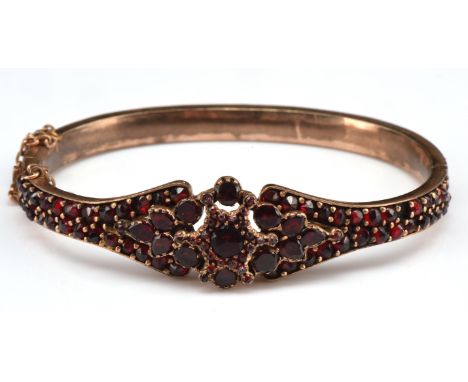 Bohemian red glass hinged bangle, with a central star design, tested as gilt metal, with concealed box clasp and safety chain