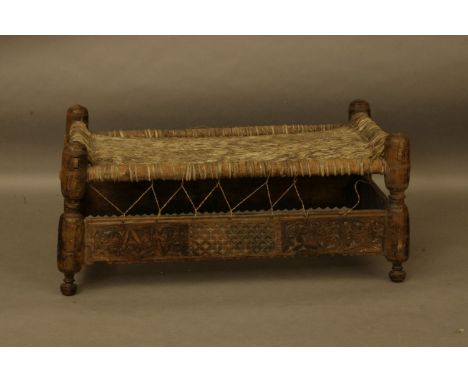 A North African carved wood and woven skin bench, 110cm wide, 60cm deep, 50cm high