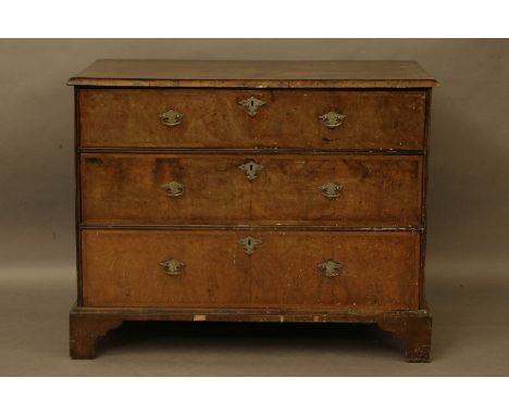 A Queen Anne walnut chest of three graduated drawers, the quarter veneered moulded top above three feather boarded graduated 