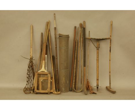 A large collection of old sporting equipment including, a lacrosse stick, a cricket bat, a vintage tennis racket, two archery