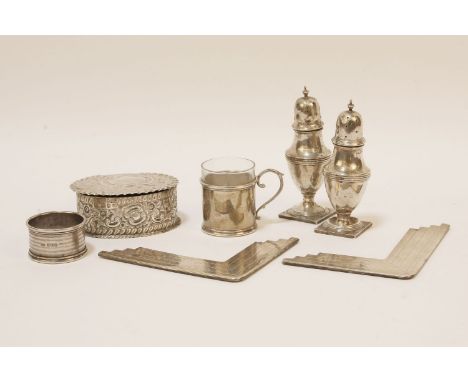An embossed silver trinket box, of oval form with 'C' scroll and flower head decoration, a pair of silver pepperettes, and a 