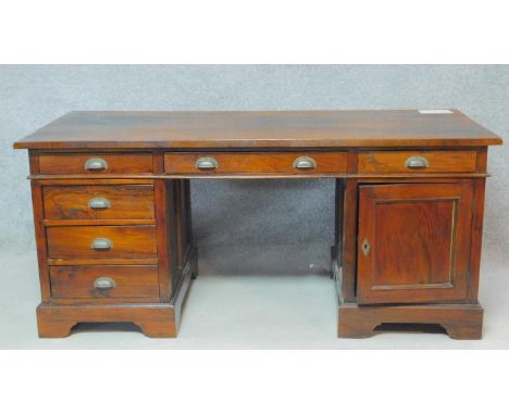 An Eastern teak three part pedestal desk fitted with a cupboard and drawers on bracket feet. H.78 W.175 D.79cm 