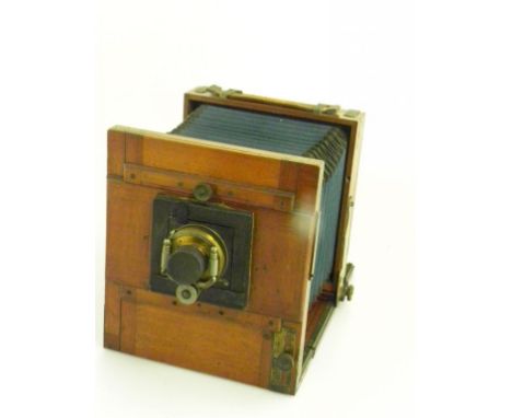 AN EARLY 20TH CENTURY MAHOGANY AND BRASS HALF PLATE CAMERA WITH LENS