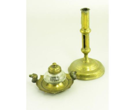 AN 18TH CENTURY ENGLISH BRASS CANDLESTICK (INCOMPLETE) AND A VICTORIAN BRASS MOUNTED GLASS INKWELL WITH HOUND'S HEAD HANDLES