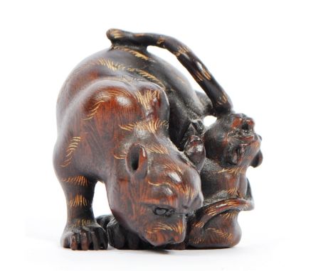 A 20th century Japanese signed carved wood netsuke in the form of a tigress with tiger cub with glass beaded eyes. Signed to 