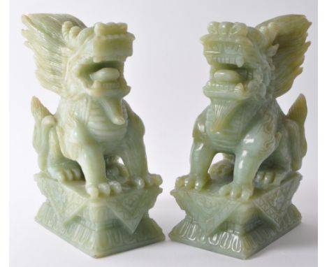 A pair of vintage 20th century jade style green stone Fu foo / temple guard dogs. In a seated posting atop a plinth base with