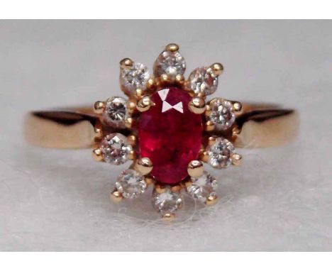 An 18ct gold tested ruby and diamond cluster ring, the central oval ruby approx. 0.6ct surrounded by ten diamonds, ring size 