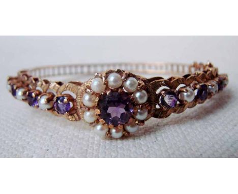 An early 20th century 9ct gold ladies bangle of openwork form, set with amethyst and pearl, centrally a single amethyst surro