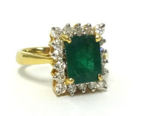 An 18ct fine emerald and diamond ring cluster ring, the oblong step cut emerald approx 2.60cts, surrounded by 18 modern round