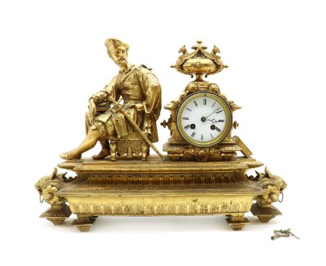 A gilt metal Empire style mantel clock,surmounted by a figure of a philosopher with a sword by his side, the white enamel dia