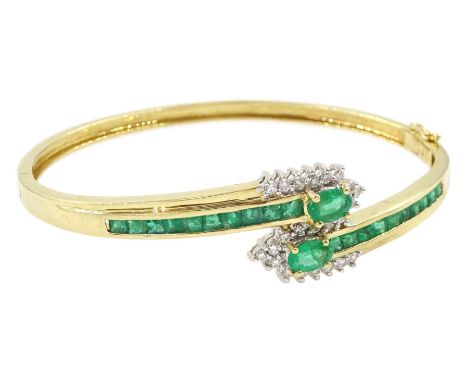 14ct gold emerald and diamond crossover bangle, two oval cut emeralds with round brilliant cut diamond surround, with channel
