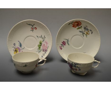 A pair of 18th century Berlin teacups and saucers, painted with colourful flowers below an ozier moulded border, septre mark,