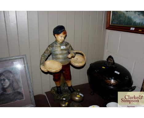 A Goldscheider style figure of a young boy carrying baskets 