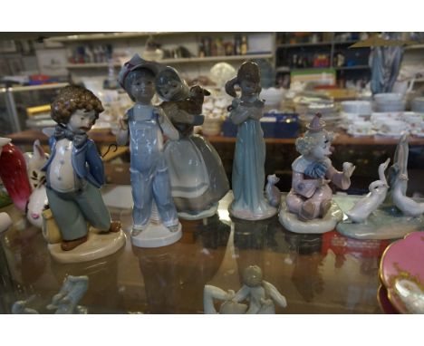 A collection of five Nao figurines to include a clown seated, a clown holding an umbrella behind his back, a musical figurine