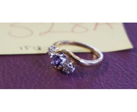 A 9ct gold gem set crossover ring, the central round cut amethyst flanked by two tiny illusion set diamonds, to crossover set