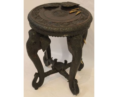 An Indian carved hardwood table, the carved circular top with meandering lotus tendrils and central elephant roundel extendin