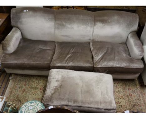 A stylish modern three seater sofa upholstered in a silver material with a matching pouffe. 