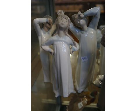 Three Lladro figurines depicting three children, two with out stretched arms.