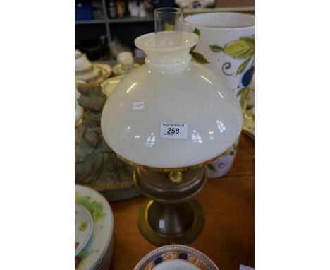 A vintage brass paraffin lamp with milk glass shade.