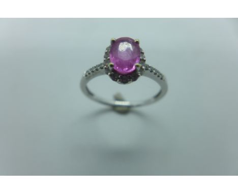 A 14ct white gold diamond and probably pink sapphire ring, the oval central stone measuring approx 7mm x 7mm, surrounded by s