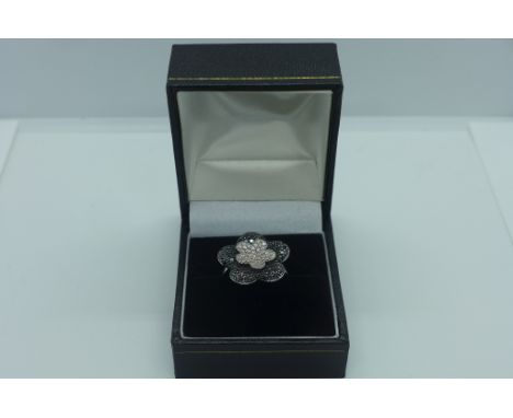 An 18ct gold hallmarked black and white diamond flower ring, size M, approx 6.8 grams, in good condition 