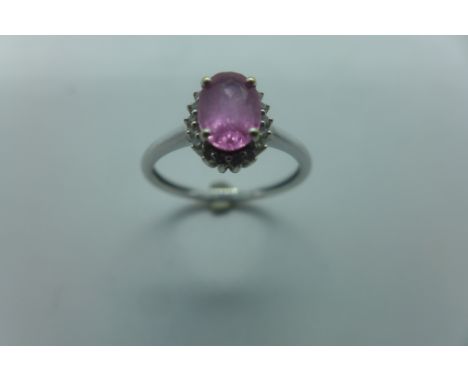 An 18ct white gold diamond and probably pink sapphire ring, the oval central stone measures approx 7mm x 5mm - surrounded by 