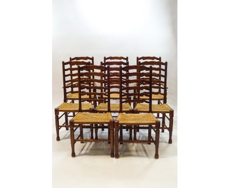 A set of eight George II style oak and ash ladder back chairs, including two with arms with rush seats on turned legs with ba