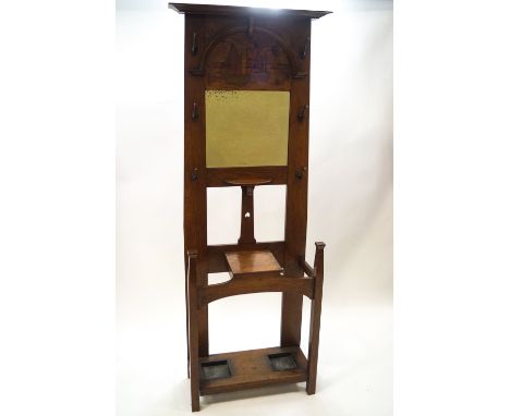 An Arts &amp; Crafts oak hall stand, the mirror back with a stained wood scene of sailing boats over a small shelf and lidded