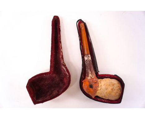 An amber pipe with clay bowl in the form of a bird with glass eyes, 15cm in length in fitted case.