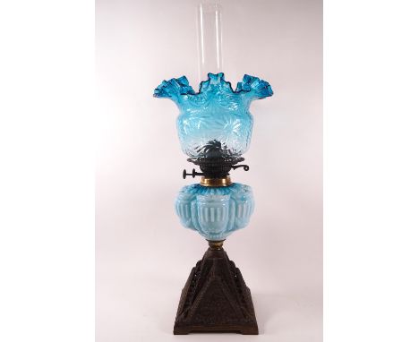 A Victorian glass oil lamp with moulded blue glass reservoir, frilled shade and funnel, on a cast iron base, 63cm high