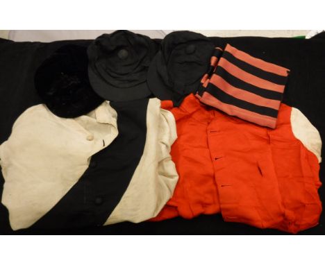 A Victorian white silk jockey jacket and cap with black sash, a red and white jockey silk jacket, black velvet jockey cap by 