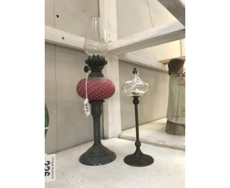 A Ruby and metal oil lamp and a wick lamp