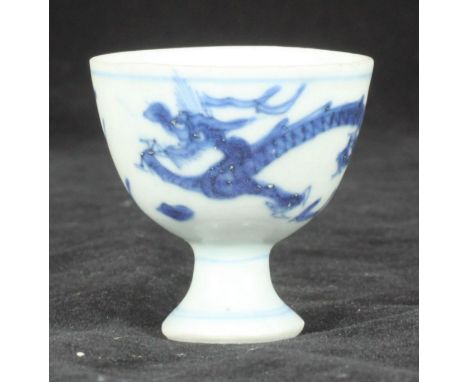 A 17th century Chinese blue &amp; white porcelain stemmed wine cup, painted with dragon chasing a pearl of wisdom, recovered 