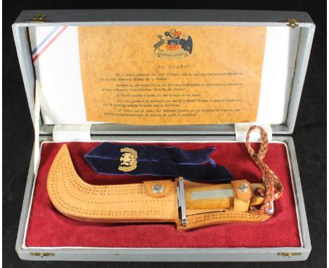 A Chilean Army 'El Corvo' knife in leather sheath and red velvet lined presentation case with an inscription detailing the hi