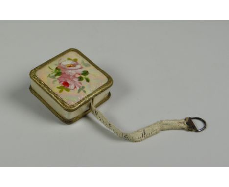 A GUILLOCHE ENAMEL-TYPE DRESS-MAKER'S TAPE-MEASURE with pretty rose decoration to the top and return button to the base (BBC 