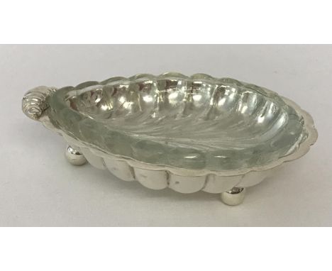 A silver plated shell shaped butter dish raised on tripod ball feet, complete with glass liner.   Approx. 13.5cm x 10cm x 3.5