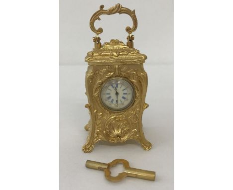 A miniature decorative, Regency style, gilt bronze carriage clock complete with key.  In working order.  Approx. 8cm tall.