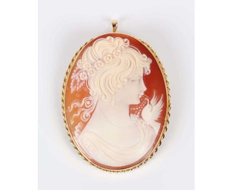 A gold mounted oval shell cameo pendant brooch, carved as a portrait of a girl with a bird, signed ‘Deri’, detailed ‘18kt Ita