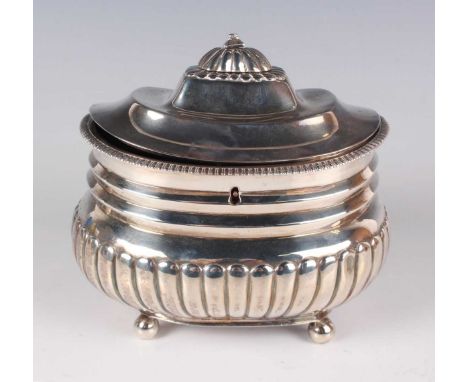A George III silver half-reeded cushion shaped tea caddy with lockable domed hinged lid and gadrooned rim, on ball feet, Lond