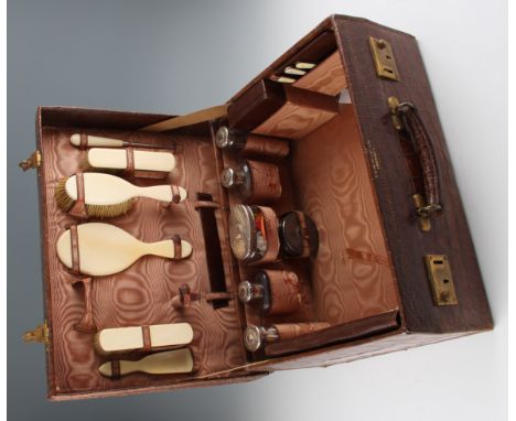 A George V sixteen piece travel set, consisting of eight faux ivory pieces to include three brushes, a mirror, a travel manic