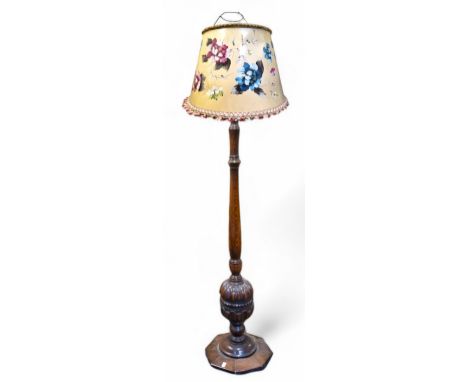 An early 20th century oak standard lamp, boldly carved, octagonal plinth base; a large flower painted lamp shade (in need of 