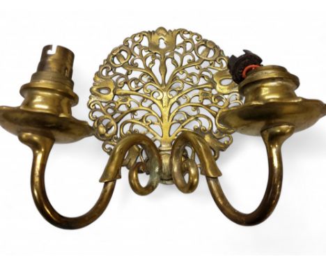 A brass two light wall light, the circular back pierced with scrolling flowering tree, 23cm wide
