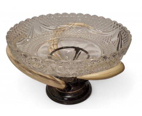 An early 20th century&nbsp;silverplate and boar tusk centre piece, the cut glass bowl resting on three silver plated mounted 